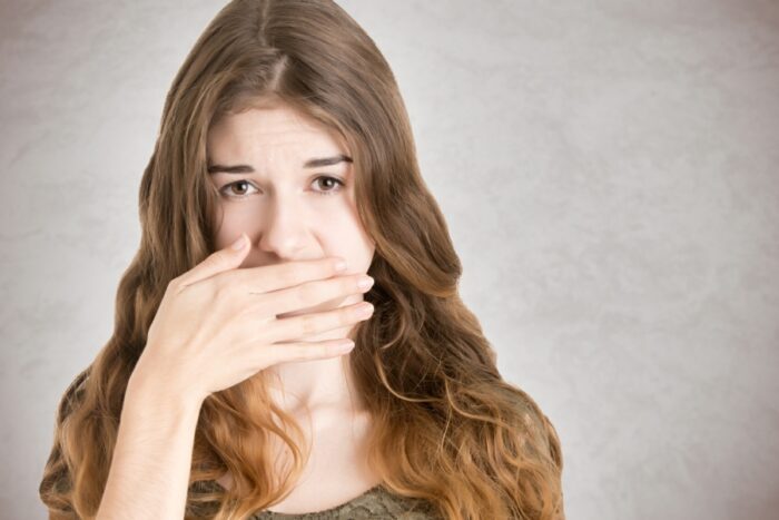 Woman with stuttering problem covering her mouth with her hand