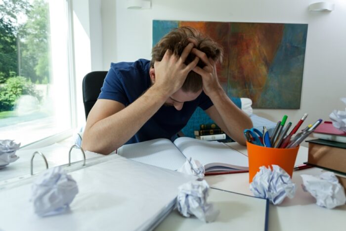 Young man with exam nerves holding his head