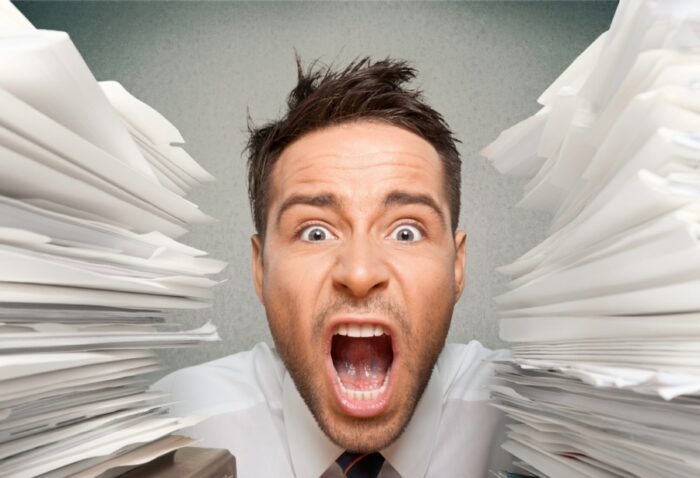 Stressed office worker between mountains of paperwork