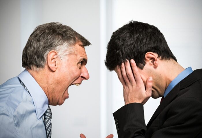 Older man shouting at young male office worker