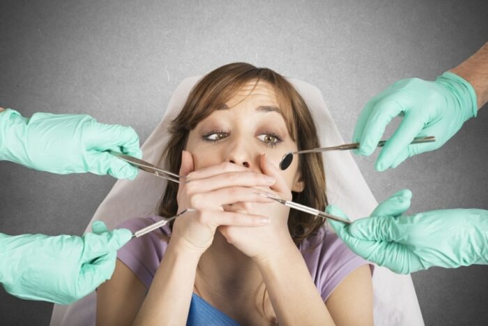 Woman with a fear of dentists covering her mouth in the treatment chair
