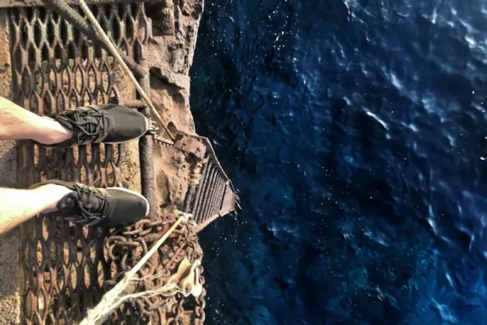 Man with acrophobia standing on platform above the sea