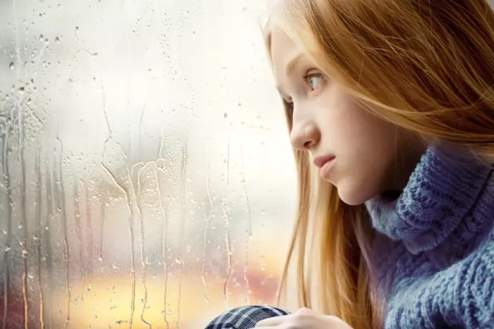 Young woman with depression staring out of window