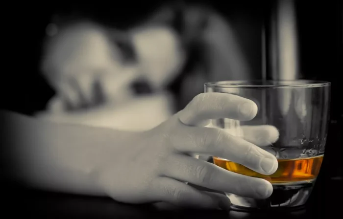 Woman staring at a glass of whiskey